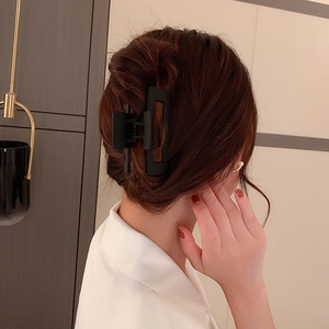 Détail d'une grande pince à cheveux carrée noir mat sur une coiffure en chignon