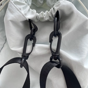 Detail der schwarzen Drehhaken und Nylongurte an einem leichten Kordelzug-Rucksack