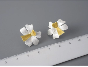 Detailed view of handmade S925 silver flower earrings with scale for size perspective