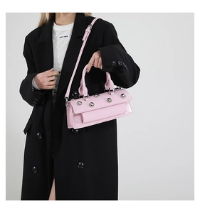 Detail showing pink patent leather bag with silver studs and detachable shoulder strap