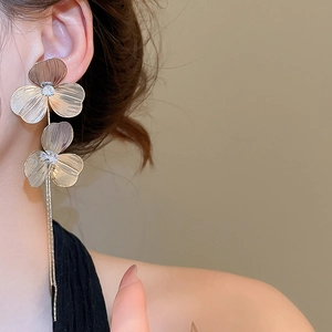Close-up of gold floral tassel earrings with zirconia inlay and brushed metal texture