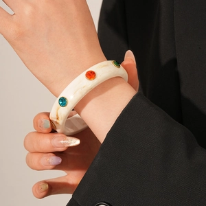 Detail of white marble resin bangle featuring multi-colored gemstones and gold accents