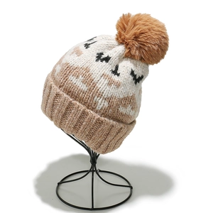 Detail of mohair knit beanie with geometric pattern and large faux fur pom-pom topper