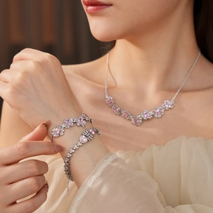 Close-up of silver jewelry set with pink flower-shaped faceted zircon stones on model