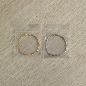 Detail of gold and silver elastic beaded bracelets on a natural wooden surface