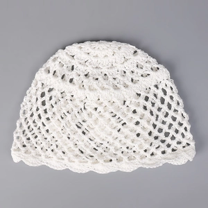 Détail d'un bonnet au crochet blanc avec motif tricoté ajouré et bordure ondulée