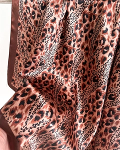 Detailed macro view of leopard print satin silk scarf fabric with glossy texture
