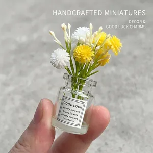 Gros plan d'un vase miniature en verre avec fleurs jaunes et blanches et étiquette Good Luck