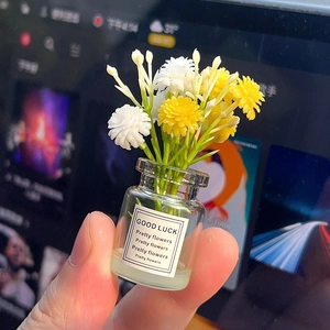 Close-up of a miniature glass flower vase featuring yellow and white flowers with Good Luck label