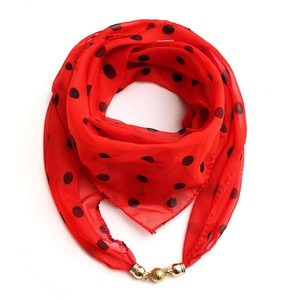 Detail of red chiffon square scarf with black dots and a gold magnetic ball buckle