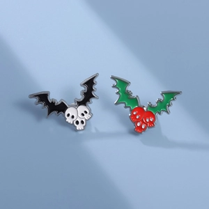 Gothic winged skull brooch set in black bat wings and green holly leaf halloween style