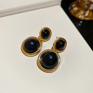 Detailed close-up of French vintage gold-rimmed earrings with black resin round pendants