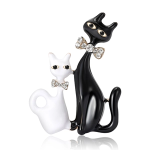Fashion enamel brooch featuring black and white cats with crystal bows on white background