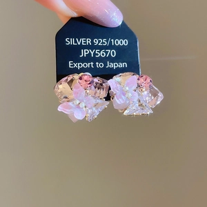 Close-up of 925 silver stud earrings with pink floral and crystal butterfly design