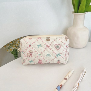 Dettaglio ravvicinato della borsa trucco trapuntata con stampe floreali e piccoli animali