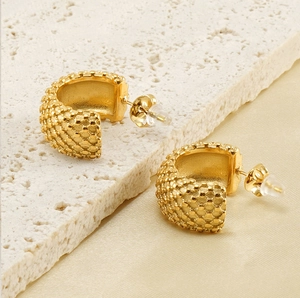 Détail de boucles d'oreilles créoles dorées en acier 18K avec motif nid d'abeille