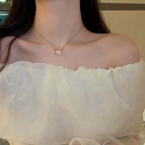 Elegant gold titanium steel necklace with a large white pearl pendant on a female model