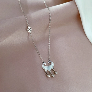 Detail of silver long life lock pendant with bells on pink silk fabric background