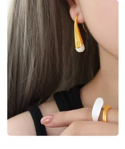 Detailed close-up of gold-plated earrings and rings with white enamel finish