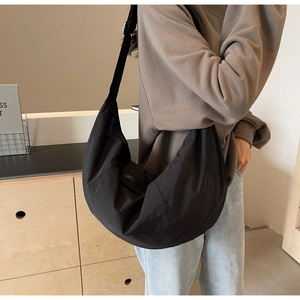 Side view of large black nylon crossbody bag on model in a minimalist setting