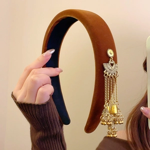 Close-up of ethnic velvet headband featuring golden jhumka bell tassels and fan design