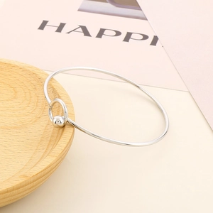 Minimalist silver stainless steel open bangle with bead detail on wooden display tray