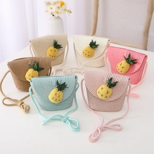 Détail de sacs bandoulière en paille tissée pour enfants avec breloques ananas mignonnes