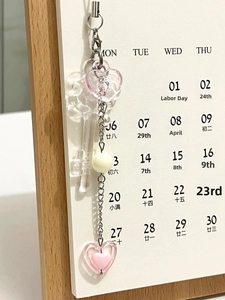Macro detail of sweet pink heart beads and white pearls on a handmade mobile phone charm