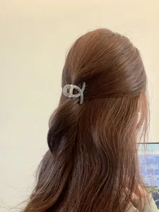 Detail of a grey resin shark hair clip securing a half-up hairstyle on brown hair