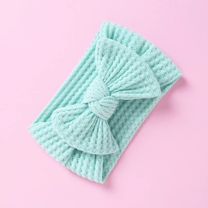 Macro detail of a light blue waffle knit baby headband featuring a soft decorative bow