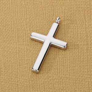 Macro shot of silver stainless steel cross pendant with polished finish on brown fabric