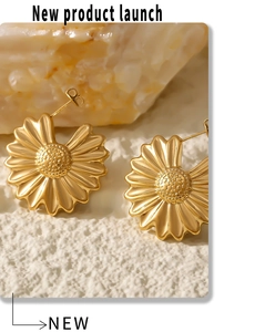 Macro shot of 18K gold plated hollow daisy earrings on white textured stone background