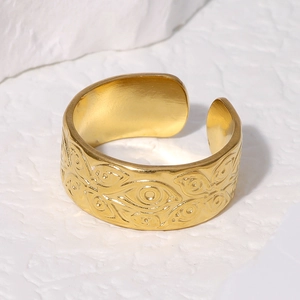 Adjustable golden stainless steel ring featuring evil eye embossed patterns on a stone surface
