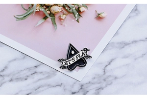 Detailed view of punk goth planchette enamel pin with Let's Play text on marble