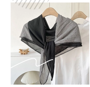 Detail of color-blocked cotton linen scarf in black and gray with lace edges