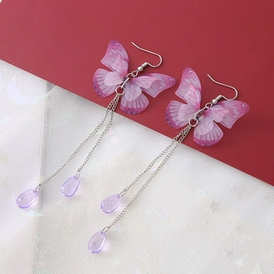 Détail de boucles d'oreilles papillon à pompons violets avec chaînes à gouttes argentées