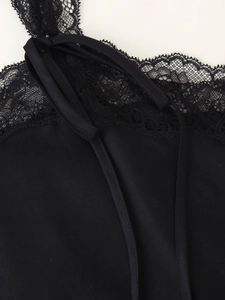 Dettaglio di un abito sottoveste in raso nero con pizzo delicato e spalline sottili