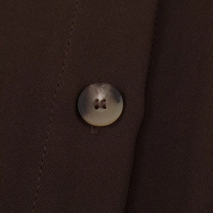 Gros plan du bouton à motif marbré sur le tissu marron foncé de la chemise tendance