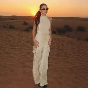 Champagne gold pleated high neck top and wide leg pants set shown in a desert sunset