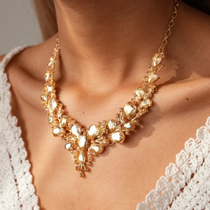 Macro shot of gold V-shaped necklace with teardrop crystals on model with lace top