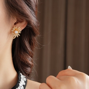 Close-up of model wearing gold sunflower earrings with pearls and zircon stones