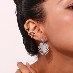 Close-up of golden and silver mixed metal earrings and ear cuffs with pearls on ear