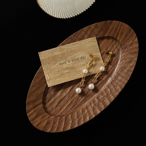 Boucles d'oreilles dorées en maillons fer à cheval avec perles sur plateau en bois