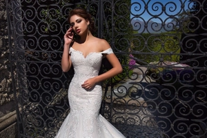 Detail of off-shoulder mermaid wedding dress featuring heavy lace appliques and mesh