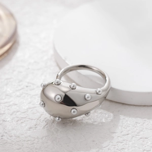 Detail of silver drop-shaped ring with small pearls on polished stainless steel band