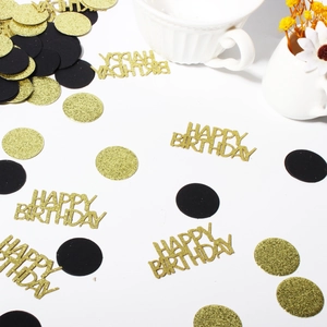 Close-up of black and gold birthday confetti with Happy Birthday glitter cutouts