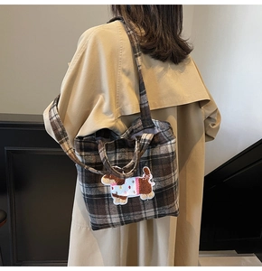 Detail of checkered tote bag with cartoon dog embroidery on khaki trench coat