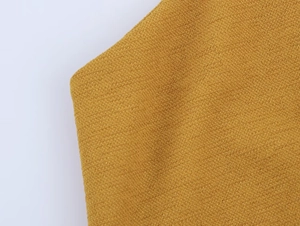 Dettaglio macro della trama in maglia giallo scuro e cuciture del vestito con scollo all'americana