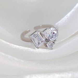 Macro shot of silver adjustable ring with pear and emerald cut zircons on white silk