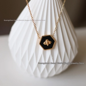 Detail shot of a hexagonal bee pendant necklace in 18K gold plated steel and black enamel
